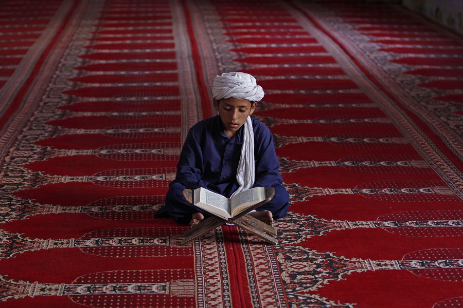 An Afghan boy reads the Quran during the Muslim holy month of Ramadan at a mosque in Kandahar, Afghanistan, Monday, July 14, 2014. For believers, Ramadan is meant to be a time of reflection and worship, remembering the hardships of others and being charitable. (AP Photo/Allauddin Khan) ORG XMIT: KND101